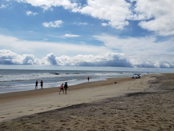 Multiple visitors enjoying a beach next to a calm Atlantic Ocean.