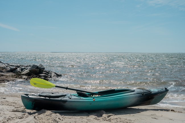 Kayak on the sand with blue water in the background