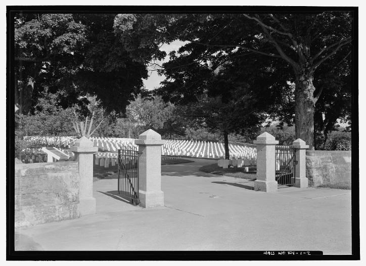 Cemetery entrance with white headstones and trees in the background in 1968.