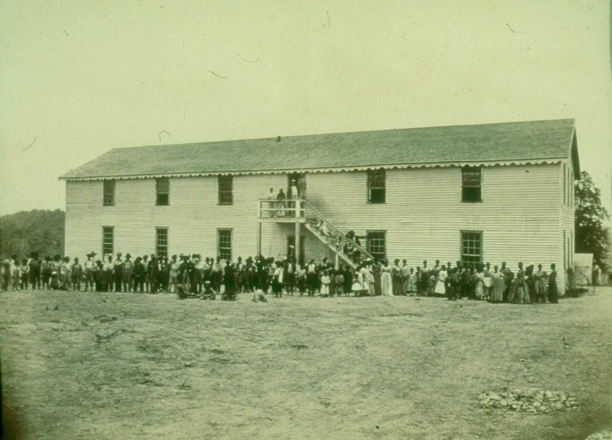 A large white building with many people standing in front of it during the Civil War.