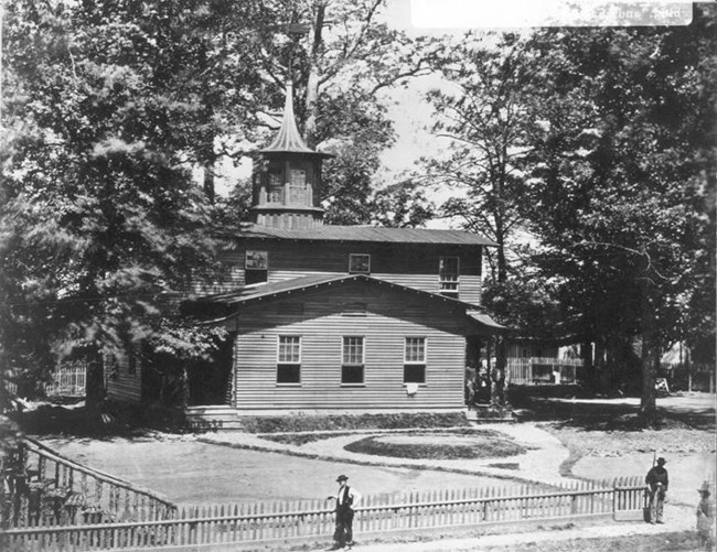 Two-story wooden building surrounded by trees and fences during the Civil War.