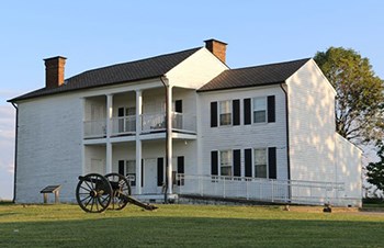 Two story wooden house with Civil War cannon in front.
