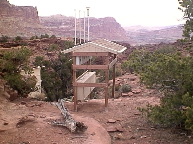 A wooden structure and roof covers electronics in a wooded area of the park.