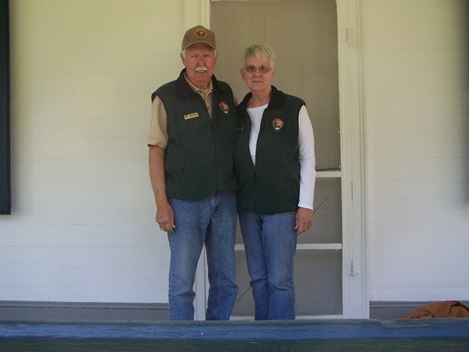 Park volunteers Don and Pat Curtis standing on the porch of the Doctor's Cottage at Oakland.