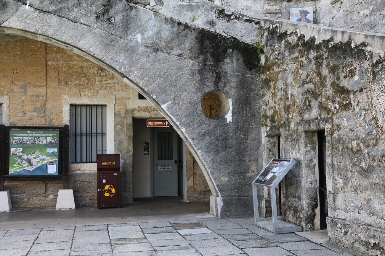 Archway with modern and historic restroom entrances.