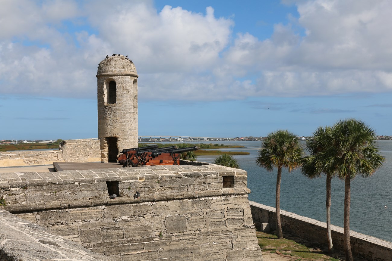 View of the northeast bastion from the gundeck with cannons, water, and bell tower.