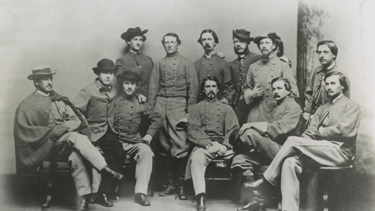 A dozen army officers sit for a group studio portrait photo.