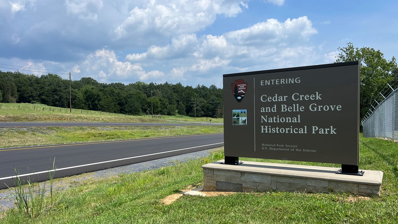 Cedar Creek and Belle Grove National Historical Park entrance sign next to a paved roadway.