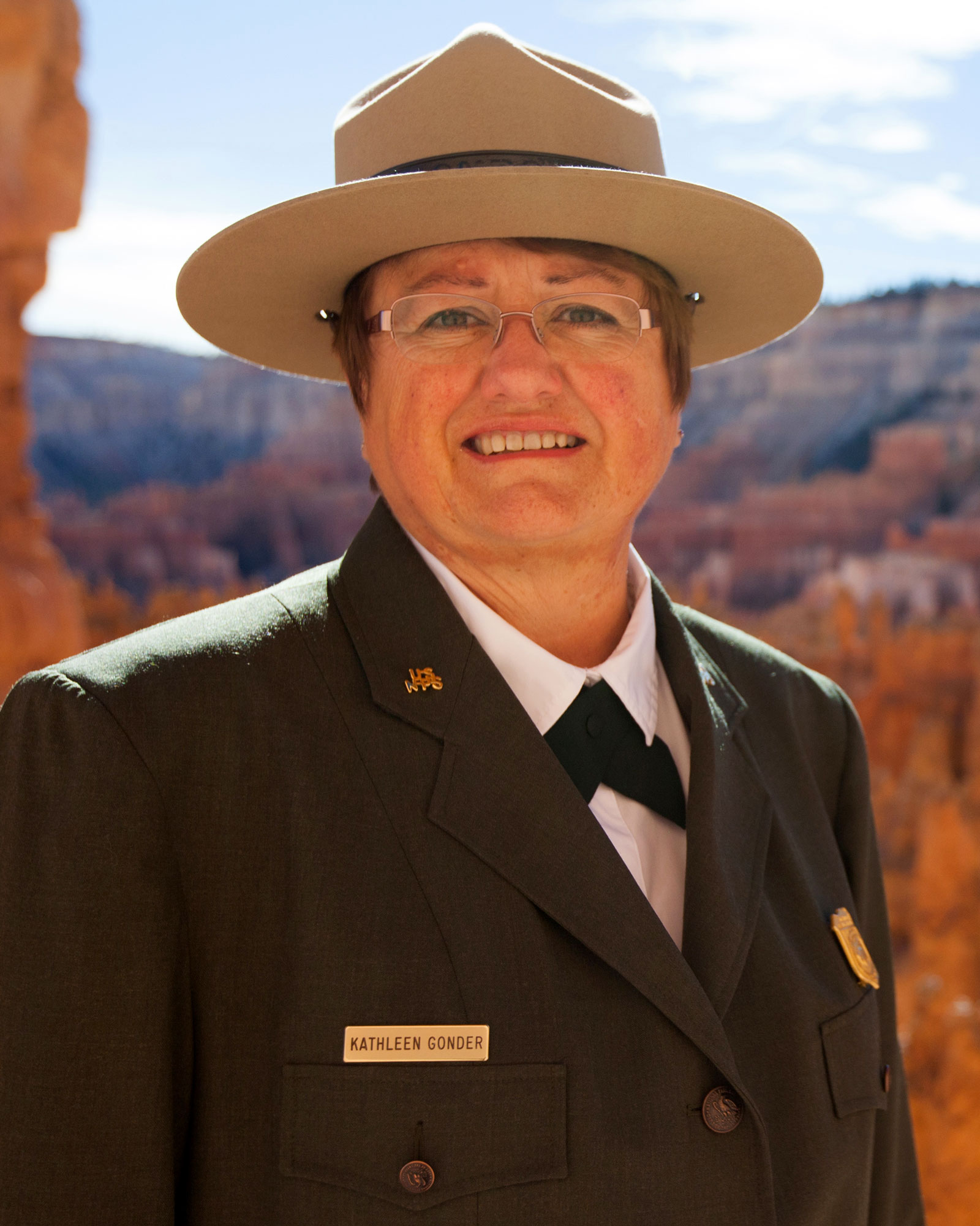 Head-shot of a woman wearing a NPS uniform, with orange cliffs in the background.