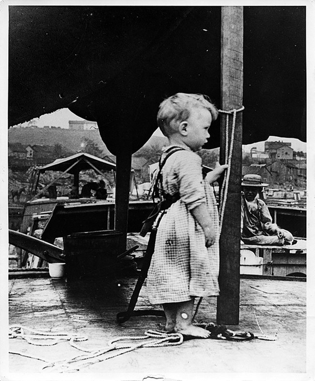 Small child tied to the cabin of a canal boat as a precaution.