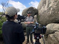 Person with camera equipment filming a ranger interview.