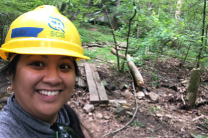 SCA Intern, Raisa Barrera, working in the field. SCA Intern Raisa Barrera in wearing a yellow hardhat in the field.
