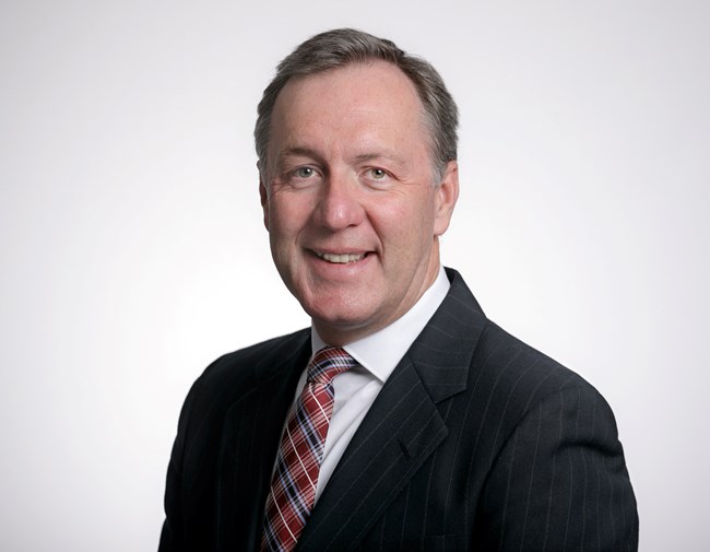 a photo of a man wearing a plaid tie, dark pinstriped suit and white dress shirt