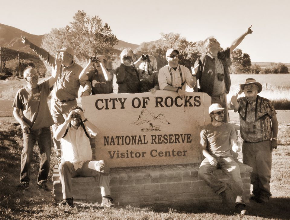 A group of birders sitting by the Visitor Center sign at the City of Rocks