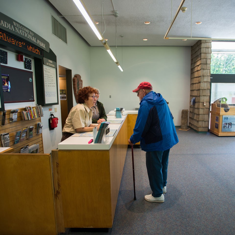 a man in a blue coat stands at an information desk