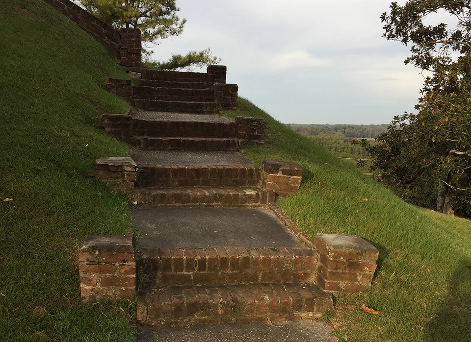 Old, worn-down brick stairs leading up to pavilion.