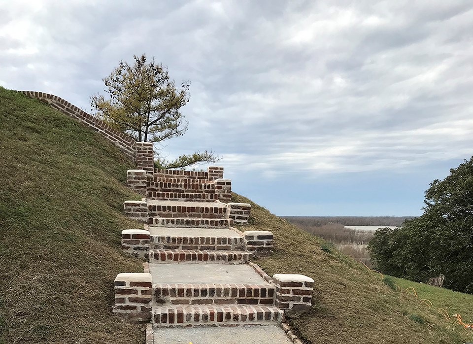 Old, worn-down brick stairs leading up to pavilion.