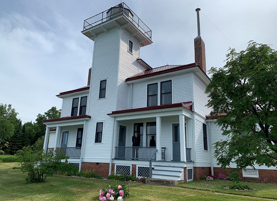 Two story white house, single home style, with a lighthouse tower on the center of the roof.