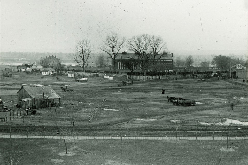 Historic landscape photo of a crowd gathered on the fort wall with various building in the backgound.