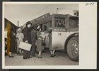 Japanese American families wait in line to board a bus.