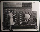 Woman operates a massive codebreaking machine with lots of rotors and dials