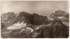 A black and white image of high view of a mountainous landscape with a glacier just left of center. 