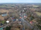 Aerial photo of village center showing a main street surrounded by trees and farm fields.