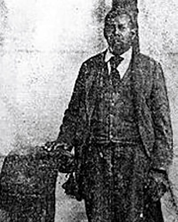A historical portrait of a man standing in a suit.