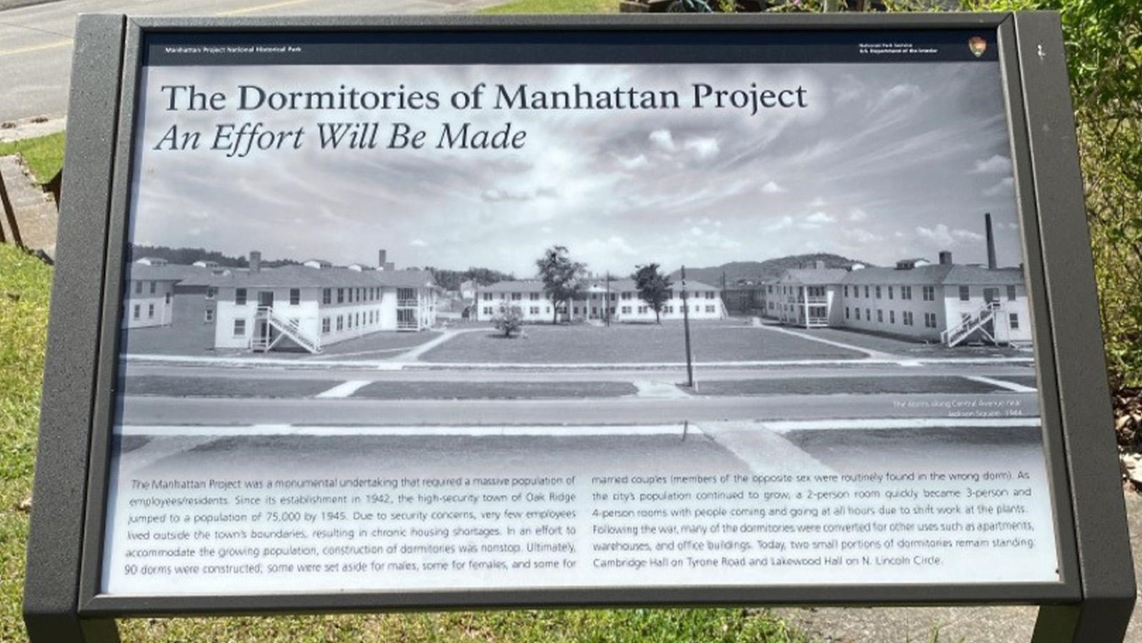 A wayside exhibit on grass in a parking lot.