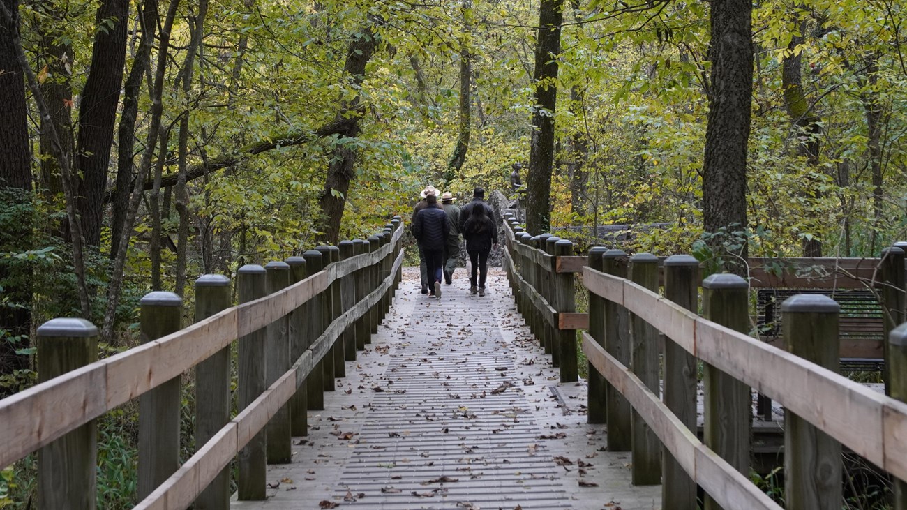 A ranger and visitor walking on a foot bridge.