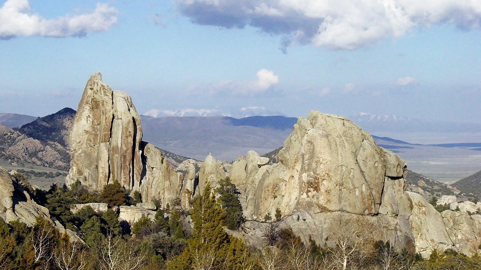 Morning Glory Spire and Anteater granite formations with large fluffy clouds floating above.