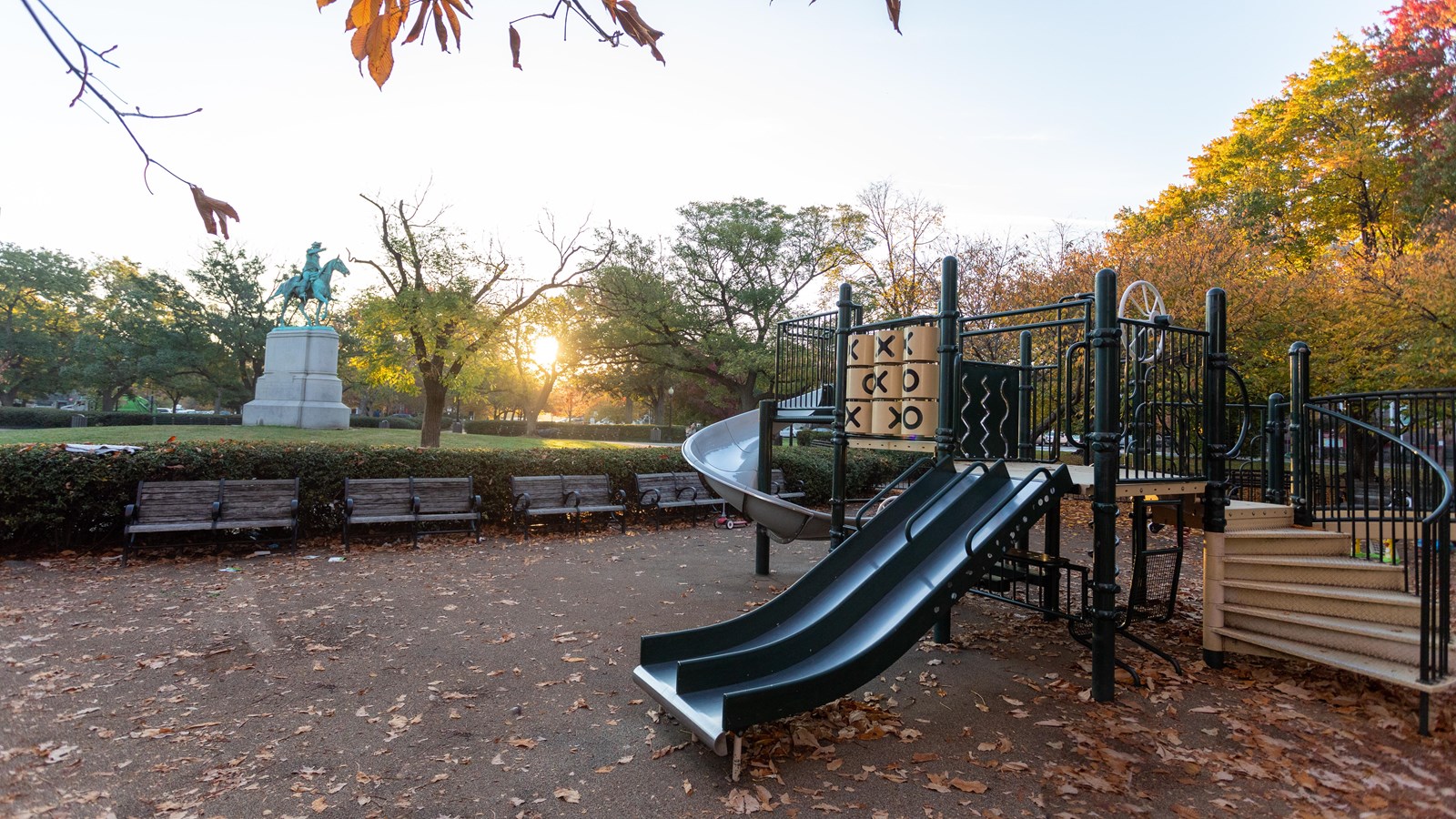 A city park contains a playground and some benches.