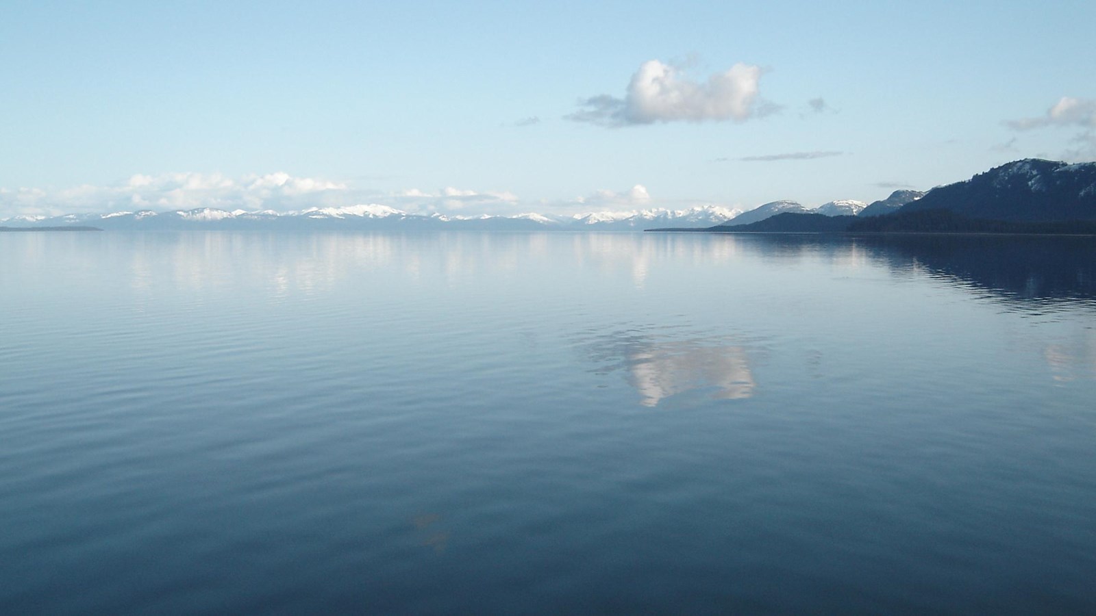 Sitakaday Narrows as as seen on a calm day. The water reflects a distant island and cloud overhead.