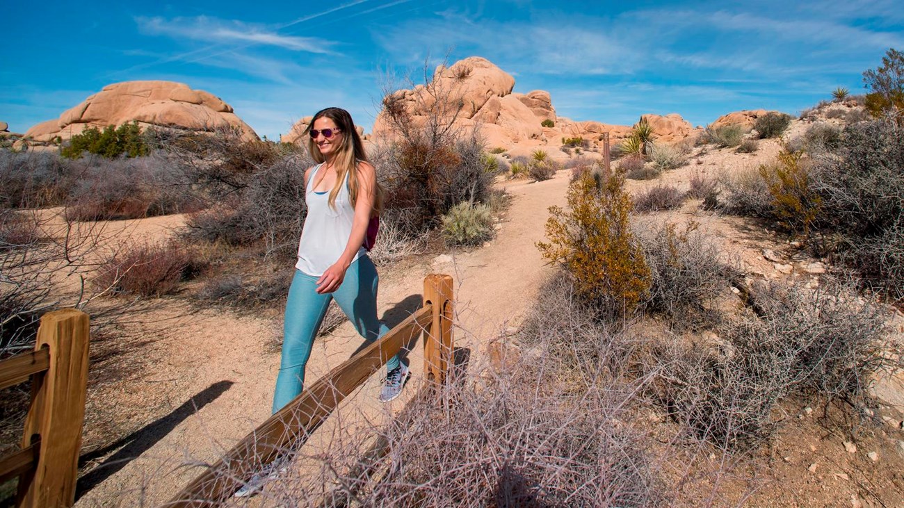 A hiker walking on a dirt trail with rocks in the background