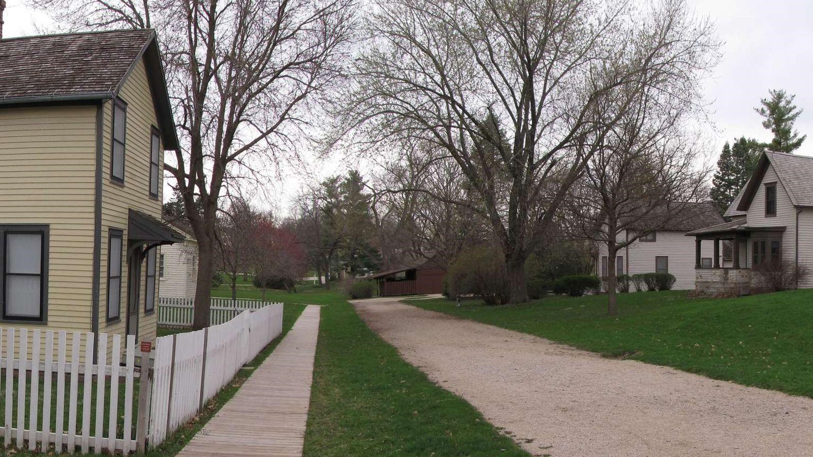 Historic homes and picket fences line the gravel trace of an old street.