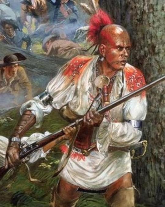 A man dressed in Native garb holding a musket towards a forested area. 