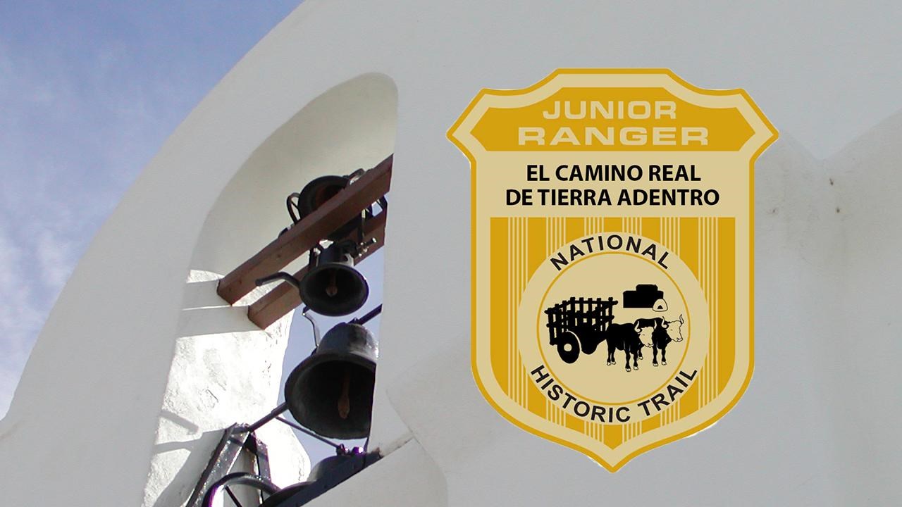 A junior ranger badge over a white stucco church bell tower. 