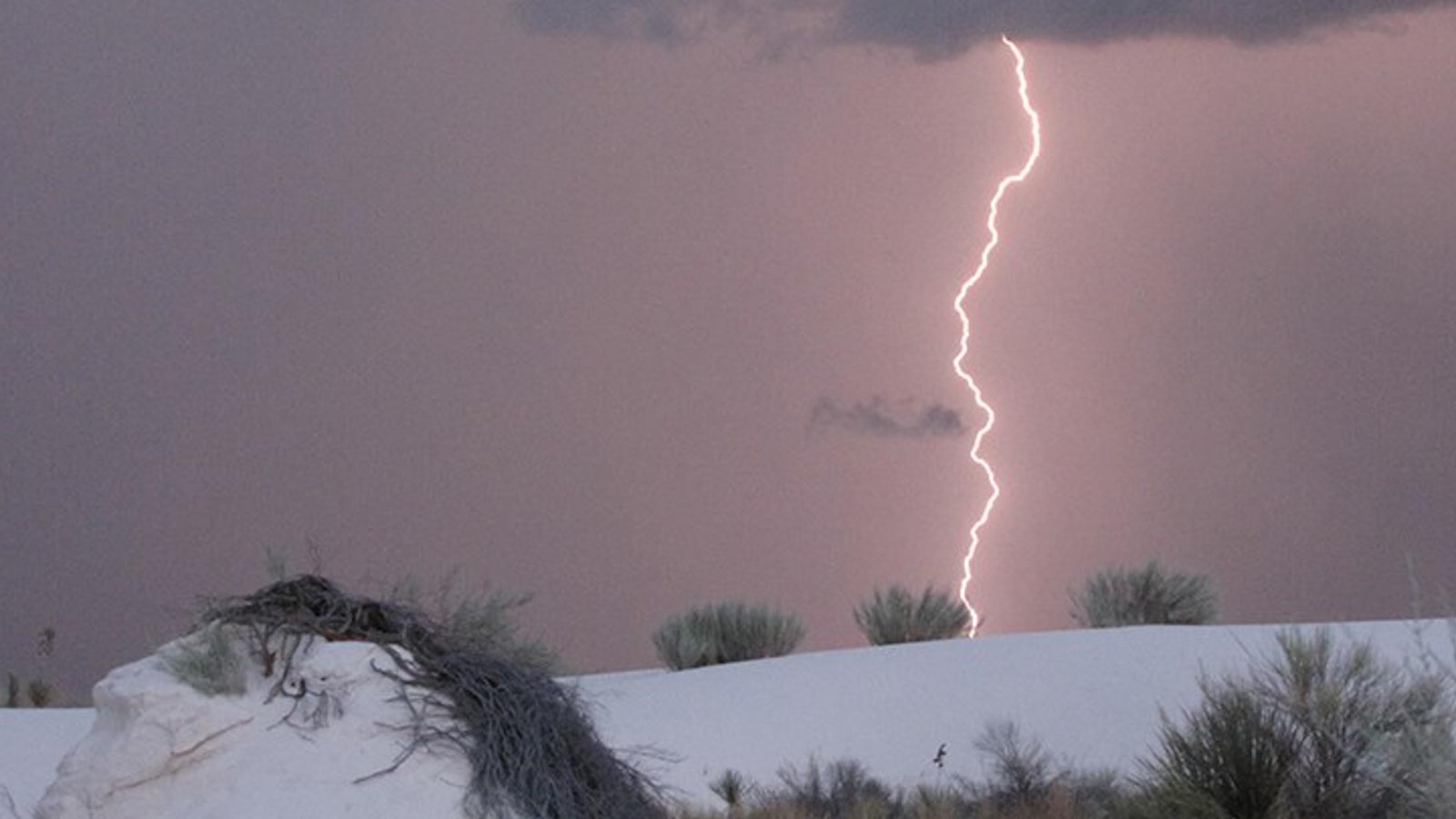 Bolt of lighting strikes white sand dune