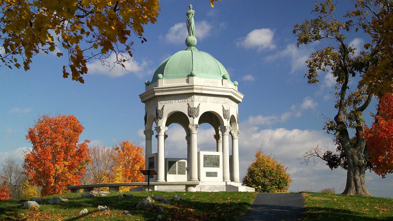 A canopied, domed monument sitting on hill in the fall time
