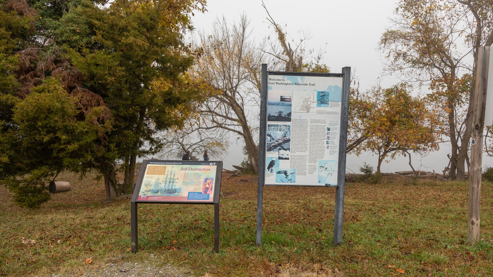 Two interpretive panels stand on the bank of the Potomac River. The panels include text and images.