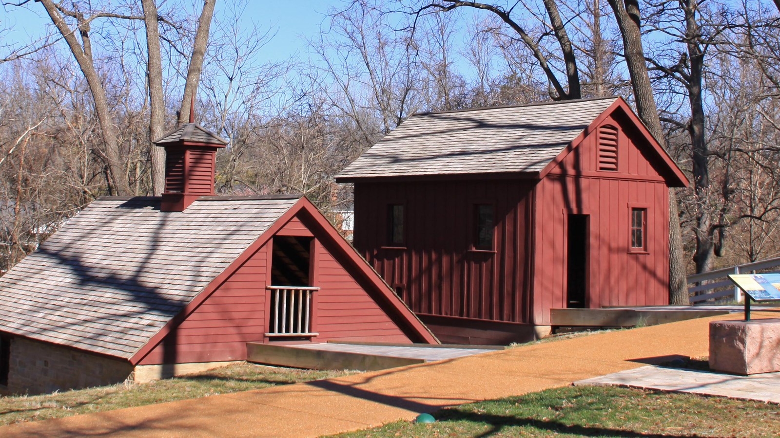 two wooden structures, painted red. Ice house is on the left and chicken house is on the right