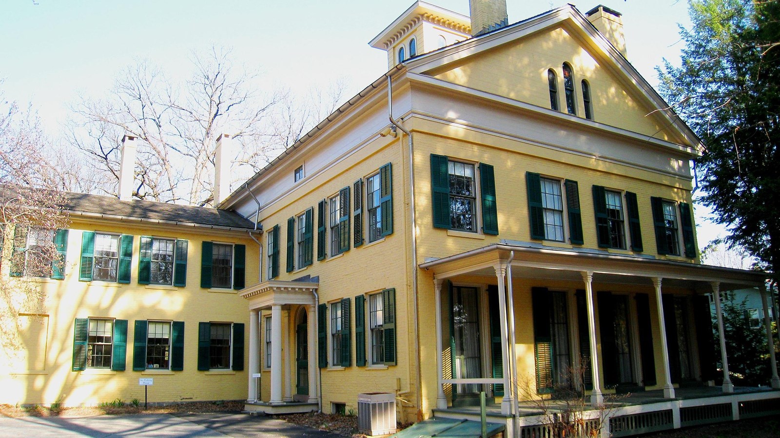 A Federal-style yellow house with green shutters and white trim. 