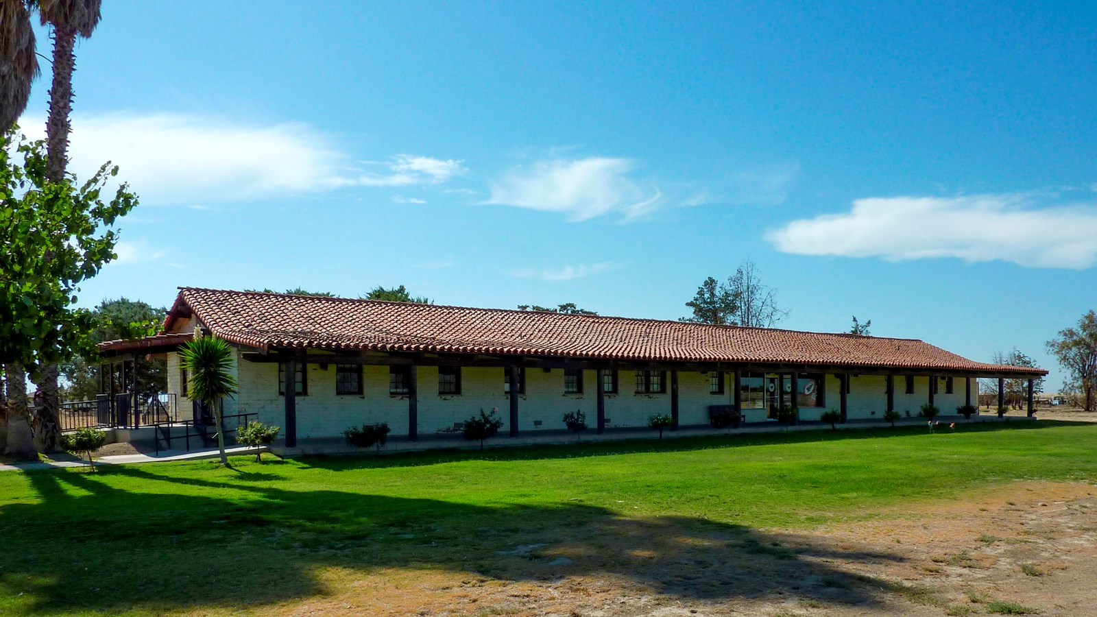 A long Spanish mission style house in an open space.