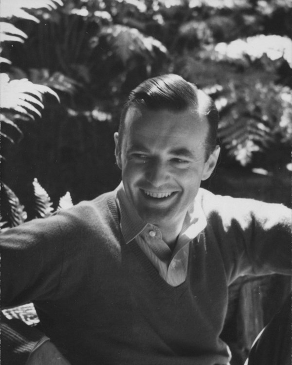 A 1941 photo depicts a young man in a sweater posing casually outdoors.