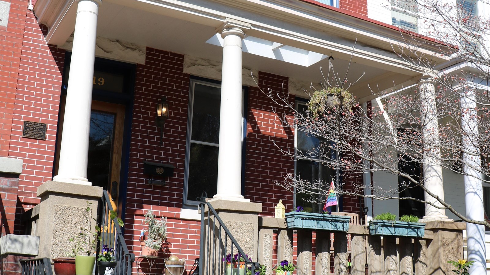 A two story brick rowhouse with white columned front porch.