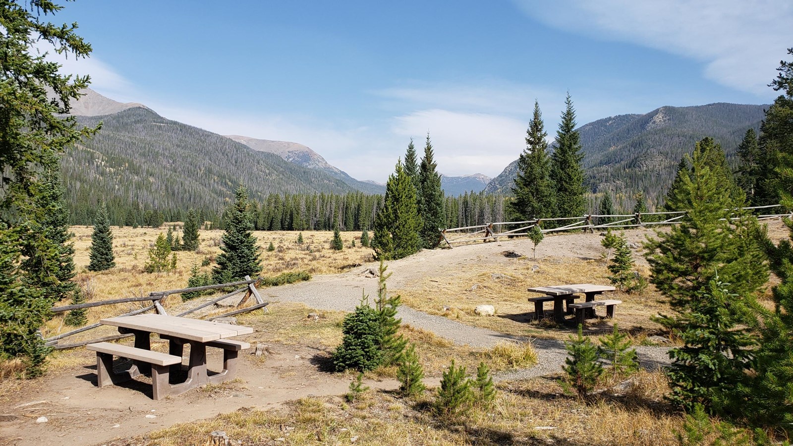 two picnic tables in an open area with mountains in the distance