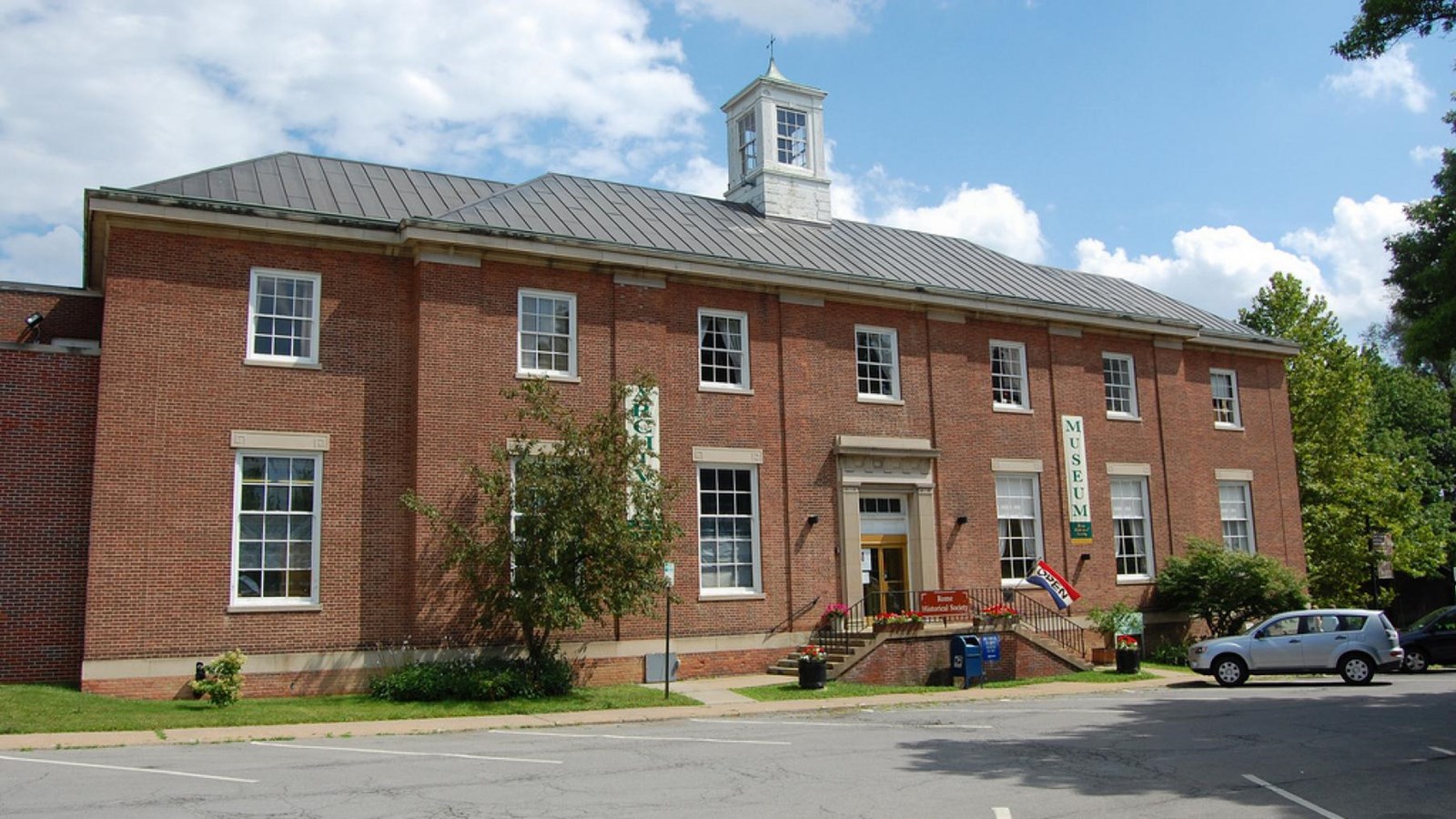 A two story brick building with a cupola. It has seven windows in the top row. 