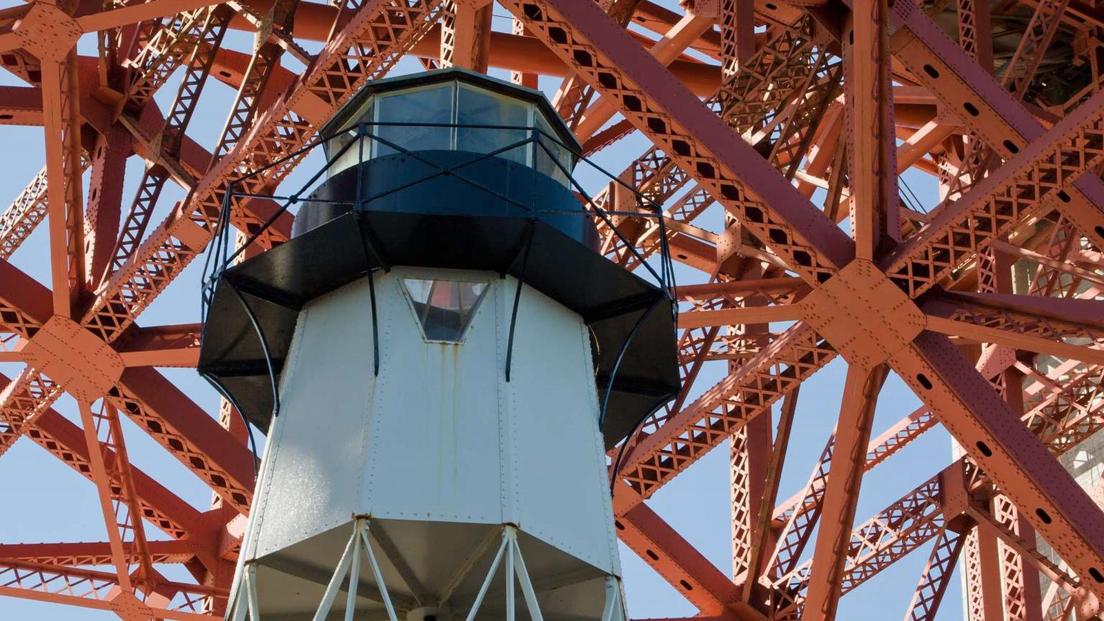 A view looking up at the Fort Point Lighthouse today with bridge ironwork above.