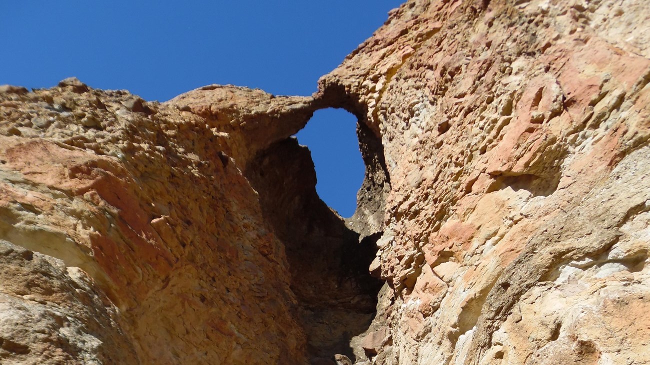A small rock arch at the top of a cliffside formed from erosion