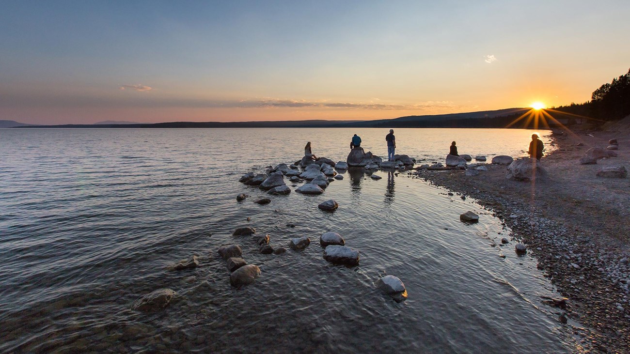 People enjoy the sunset from the shore of Yellowstone Lake.